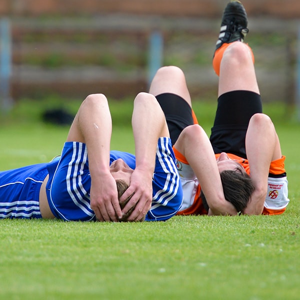 soccer players holding heads lying on ground