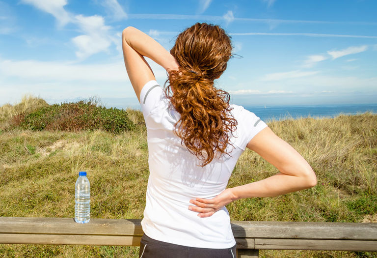 woman stretches upper body while outdoors