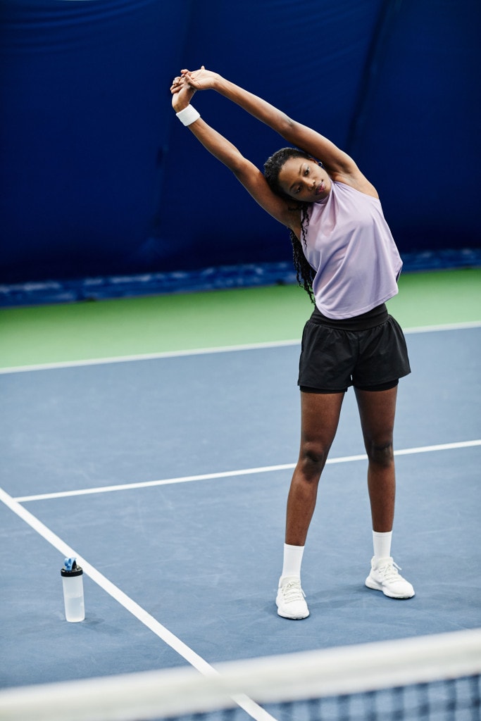 woman stretching on tennis court