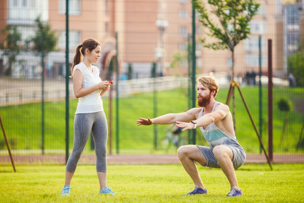 man and woman do dynamic warm up outdoors