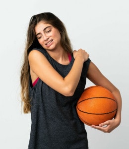 young basketball player holds her shoulder in pain