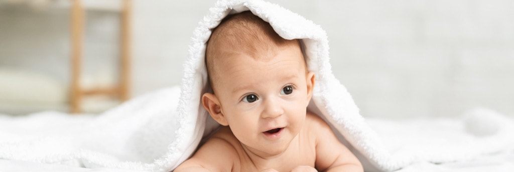 baby tummy time happy peeking from under a towel