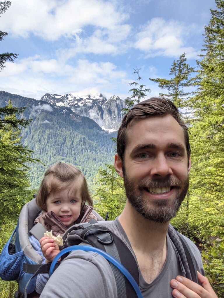 physical therapist Devin Langaker hiking with daughter in backpack in the mountains.