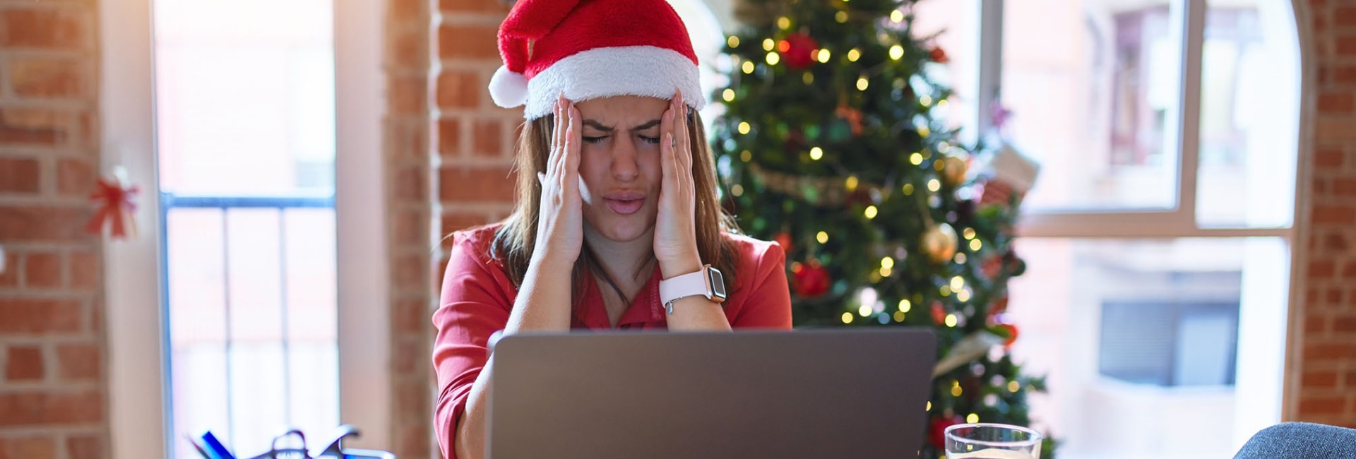 woman holds her head in response to a stress headache at the holidays