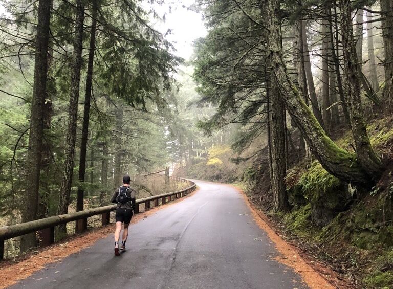 man running on a remote road in the PNW forest