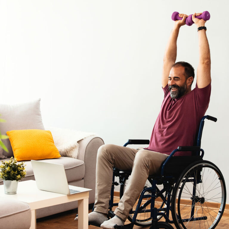 man reaches overhead with dumbbells during exercise in a wheelchair